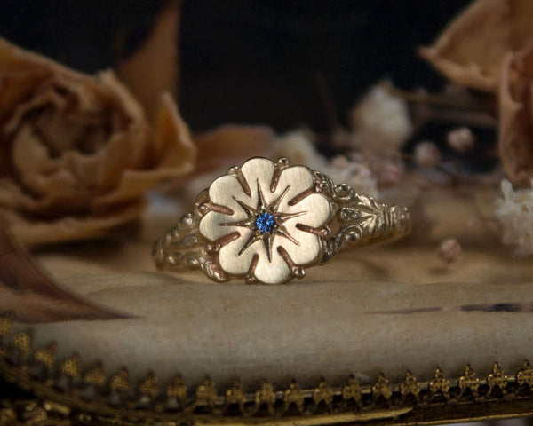 Vintage style flower ring with a blue sapphire center, front view